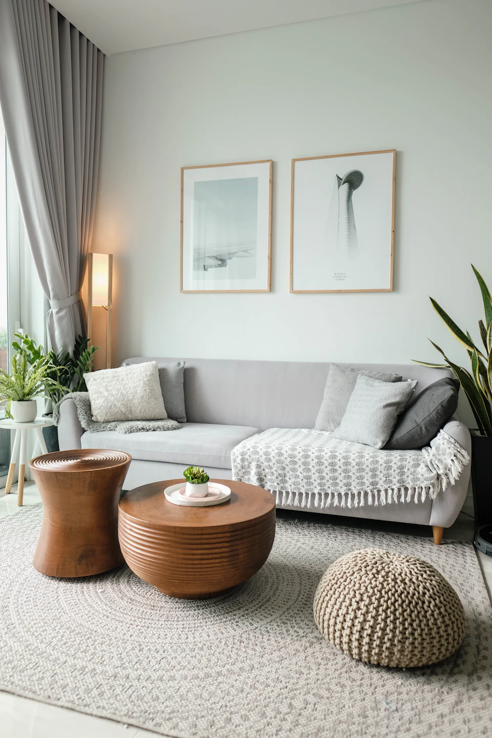 A quiet living room with a low sofa, a round timber table and framed prints
